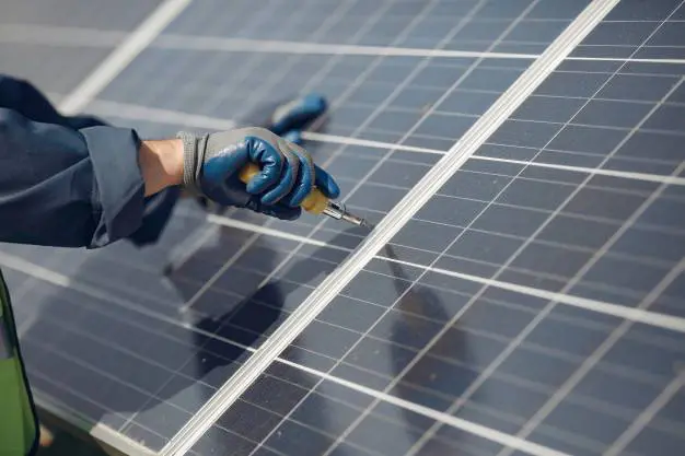a person holding a screwdriver on a solar PV panel. Installing solar panels in the wellington region.